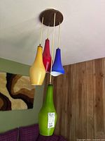 Overall view of four colored glass shades hanging from woodgrain canopy.