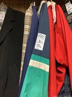 Photo of six men's jackets hanging, including solid dark blazer, plaid blazer, navy jacket with yellow stitching, teal windbreaker with stripes, royal blue and red windbreakers.