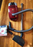 Red Miele vacuum with hose, wand, floor tool and AirClean box