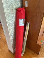 9-ft patio umbrella in red carrying case standing against wall.