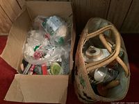 Top view of cardboard box filled with plastic bags containing buttons, threads, measuring tapes, and other sewing supplies