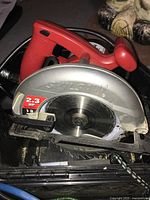 Close-up of Skilsaw circular saw showing blade, red handle, and attached power cord.