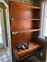 Front view of full teak wall shelving unit mounted, showing three shelves and drawer unit