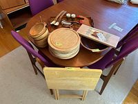 Entire lot on wood dining table showing wood bowls, plates, cutting boards, condiment set, cedar plank and folding table.
