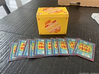 Closed yellow Score Rookie and Traded box with trivia cards spread in front