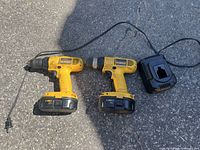 Overall lot showing two drills, two batteries attached, and charger with cord