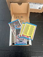 Cardboard box filled with 1989-90 O-Pee-Chee hockey cards, visible Grant Fuhr card and two checklist cards