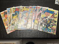 Group shot of eight bagged Avengers comic books laid out on table