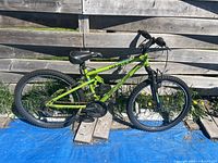 Full side view of green Nakamura Monster bike against fence