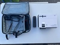 Projector, remote, open carrying case with HDMI cable visible