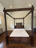 Full frontal view showing entire four poster bed with box spring inside the frame, posts at each corner and canopy framework on top.