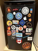 Front view of black Danby mini fridge with numerous colorful decals and stickers covering the door surface.