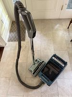 Full view of the Hoover Dimension 900 upright vacuum with hose and hand control on tiled floor.