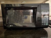 Front view of black LG Intellowave microwave oven with control panel and door with window.