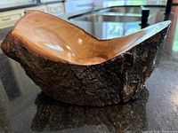 Side angled view of live-edged wooden candle holder showing bark texture and smooth lacquered inner surface with candle recess.