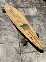 Top side of the Sector 9 longboard showing natural wood finish, deck length, and width with some graphics visible.