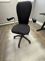 Black swivel office chair viewed from the front sitting on a translucent floor mat
