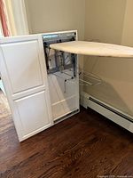 Wall mounted ironing board partially extended with ironing surface visible and metal drying rack attached underneath