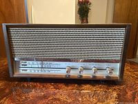 Front view of vintage AM/FM radio showing speaker grille, tuning dial, and control knobs