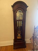 Full front view of the floor clock showing overall design and wood finish
