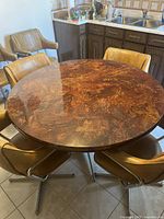 Top-down view showing the round dining table surface with wood veneer and the six attached chairs in a kitchen setting.