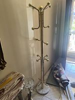 Full view of the gold metal coat rack showing the height, design and multiple hooks.