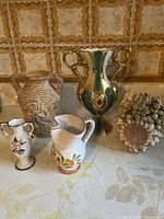 Photo showing full set of five decorative vases of varied styles and sizes on display surface with ornate tiled background.