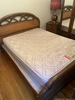 Photo showing the queen size bed frame with mattress and boxspring assembled, highlighting the wooden headboard and laminate finish.