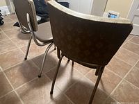 Photo of backside of two vintage metal and vinyl chairs showing patterned vinyl upholstery.