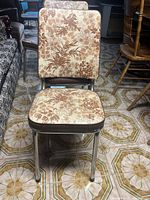 Front view of chair showing floral upholstery on seat and backrest with chrome metal legs.