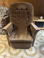 Front view of brown fabric armchair featuring button-tufted padded backrest, cushioned seat, and armrests. Visible wear and fabric discoloration apparent.