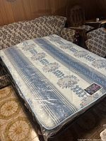 Futon sofa in a reclining position showing a floral patterned mattress with blue and white colors and floral accents.