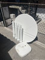 Table disassembled showing tabletop, four legs, and a weighted base piece, all white plastic.