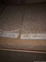 Two beige cotton towels laid flat showing leaf pattern and embroidered floral borders