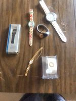 Group shot of all wristwatches, boxed watch, and ring on table