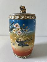 Front view of the jar showing bird and cherry blossom hand-painted decoration with foo dog finial lid