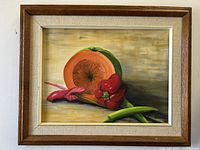 Frontal view of the framed oil painting showing the cantaloupe, red pepper, and other vegetables with artist signature visible.
