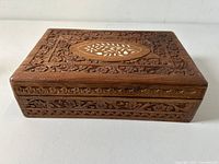 Rectangular carved fruitwood box with floral carving and inlaid central motif on lid
