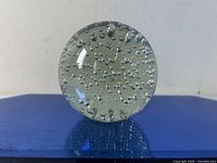 Front view showing clear spherical paperweight with numerous small controlled air bubbles uniformly distributed inside.