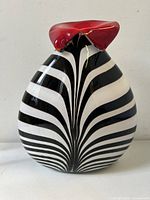 The front view showing zebra stripes converging towards the center and the red folded top opening of the vase.