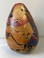 View of the gourd vase showing the figure in traditional attire and elk motif in hand-painted indigenous style.