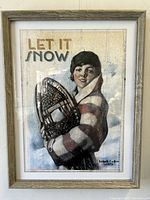 Front view of the framed art print titled 'Let It Snow' showing a woman holding snowshoes with art deco style lettering and colors.