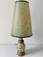 Front view of the lamp showing the textured cone shade and pottery base with geometric circular design.