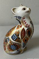 Porcelain Siamese kitten figurine showing side view with detailed Imari pattern in gold, red, blue, and black.