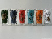 Front view of the six Libbey apothecary highball glasses in a row showing different colored designs.