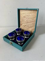Set of four silver plated salt cellars presented in a teal vintage box with dark blue interior fabric lining.