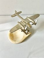 Angled view showing vintage chrome twin-propeller airplane mounted on an oval marble ashtray base.