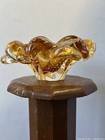 Side angled view of amber glass bowl showing wavy ruffled edges and controlled bubble detail on the interior.
