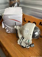 EasyN 10R security camera outside of box showing dome shape with antennas, wired connections and mounting bracket. Box is torn and damaged.