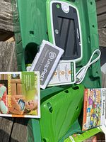 Leap Pad 3 tablet with green gel skin case, charging cord, instruction booklets, and Letter Factory Reading game box.
